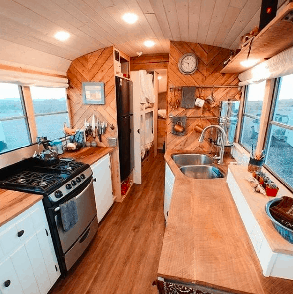 Bright and spacious skoolie interior showing a full skoolie kitchen. 