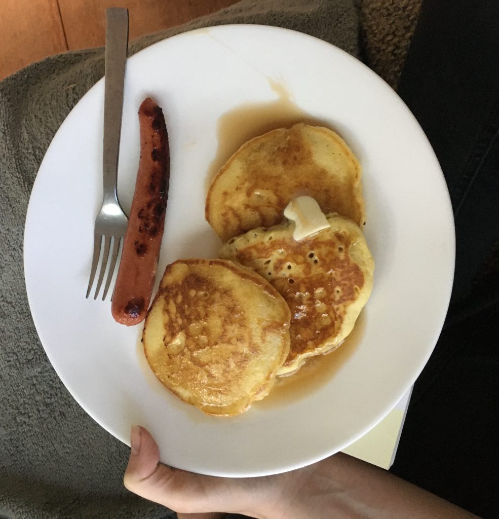 Plate showing pancakes and a sausage. 