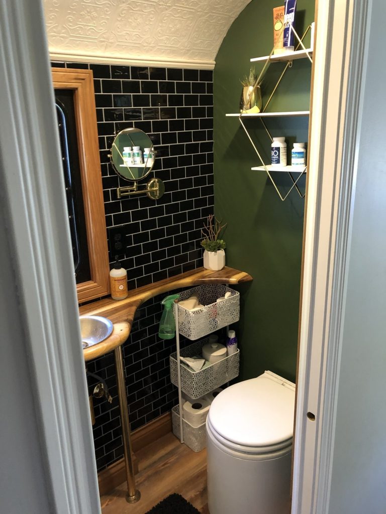 Stylish skoolie bathroom with dark tile and wood countertops.