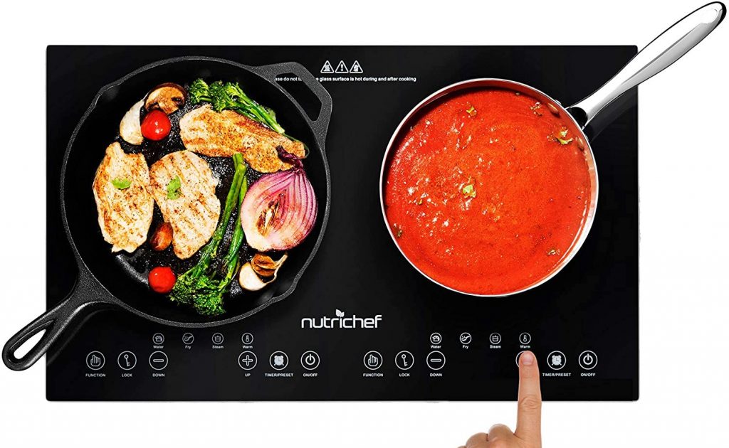 Double-wide induction cooktop showing chicken being cooked in one pot and sauce being cooked in another pot. 