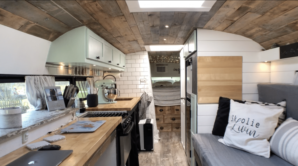 Cozy and modern skoolie interior, showing a kitchen and eating area, from Skoolie Livin'