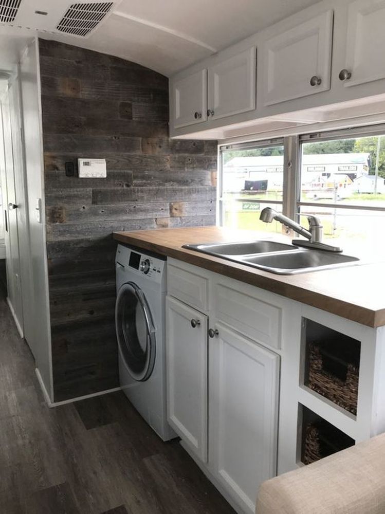 Photo of a skoolie kitchen that includes a combo washer/dryer under the countertop. 
