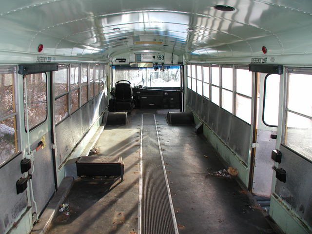 Skoolie conversion in progress, showing a bus interior with the seats removed. 
