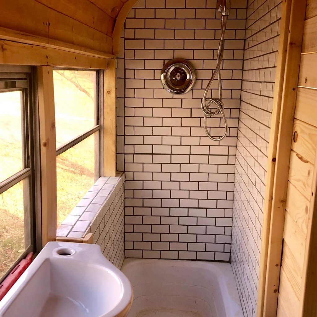 Interior of a skoolie bathroom in progress, with white subway tile. 