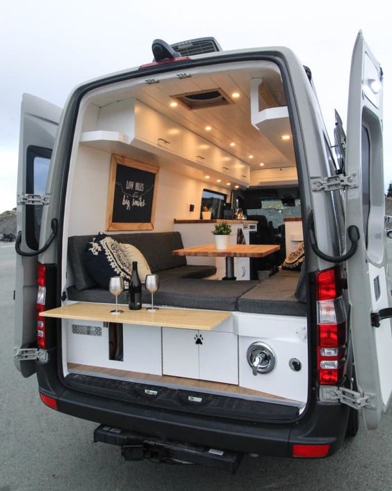 Open view of the back of a vanlife van showing a modern interior set up for dinner. 